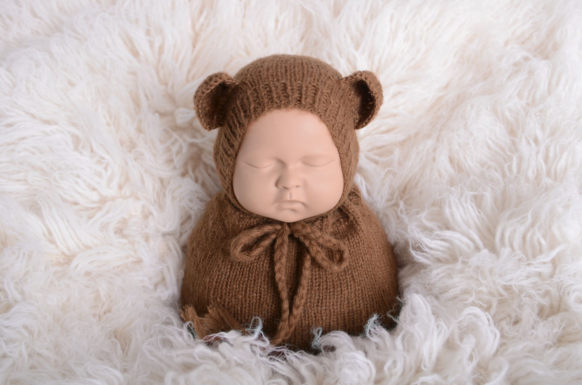 Newborn photography prop featuring a beige mohair bear bonnet and sack on a plush white background, designed for a serene and soft aesthetic.