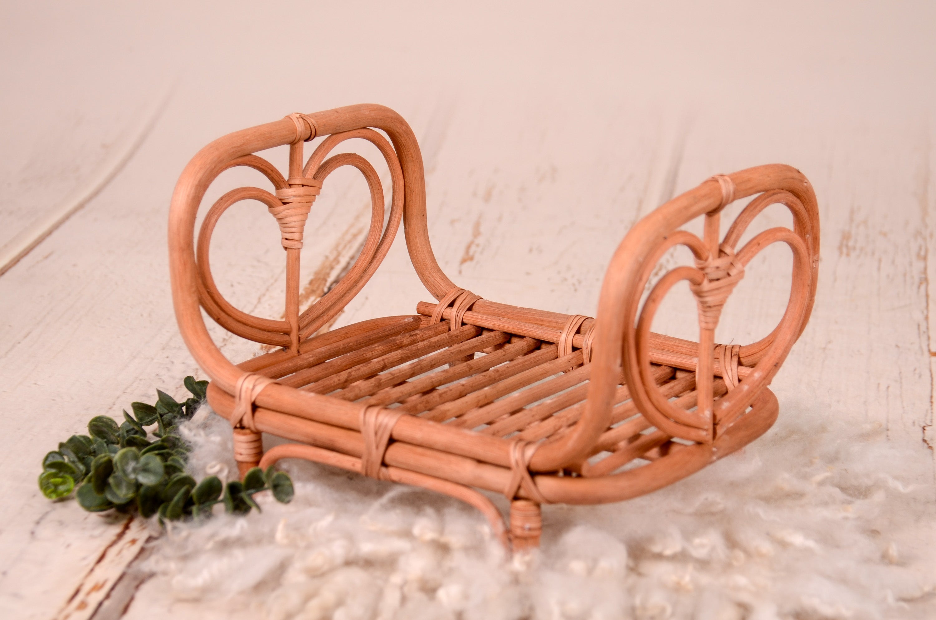 Rattan love nest newborn photography prop on a soft, fluffy rug.