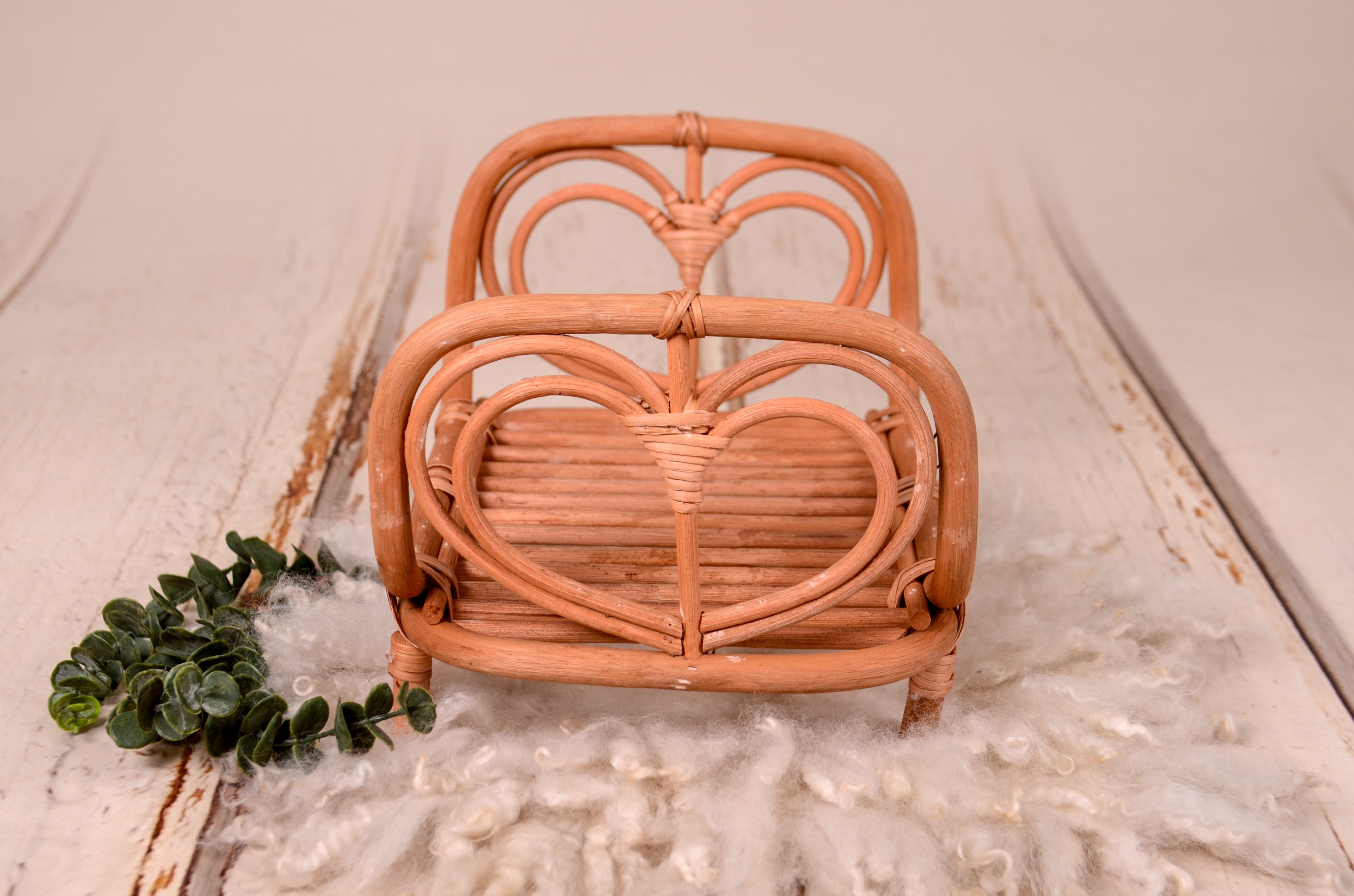 Rattan love nest newborn photography prop on a soft, fluffy rug.