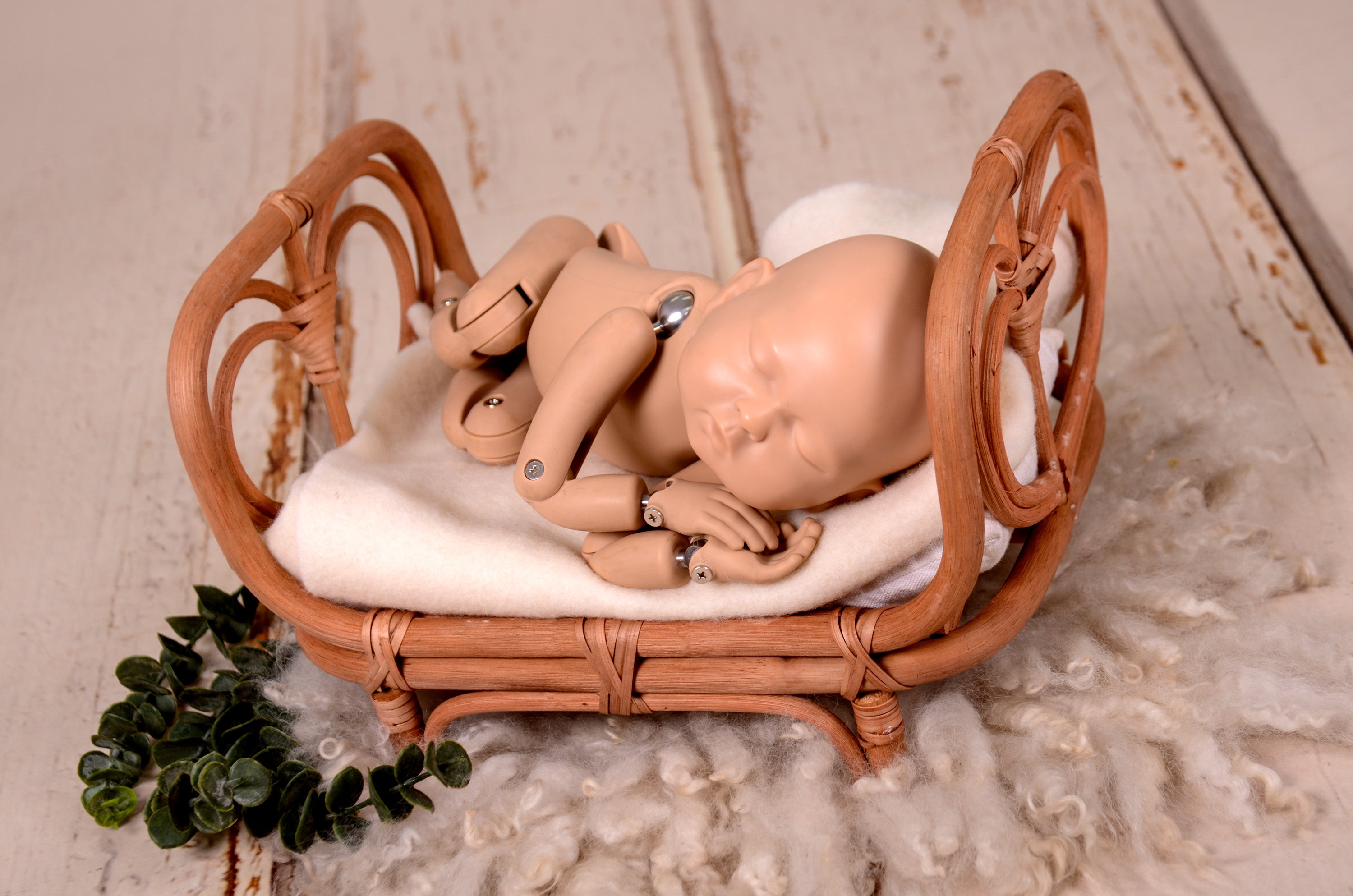 Rattan love nest newborn photography prop on a soft, fluffy rug.
