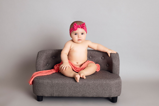 Baby sitting on a mini sofa prop for newborn photography