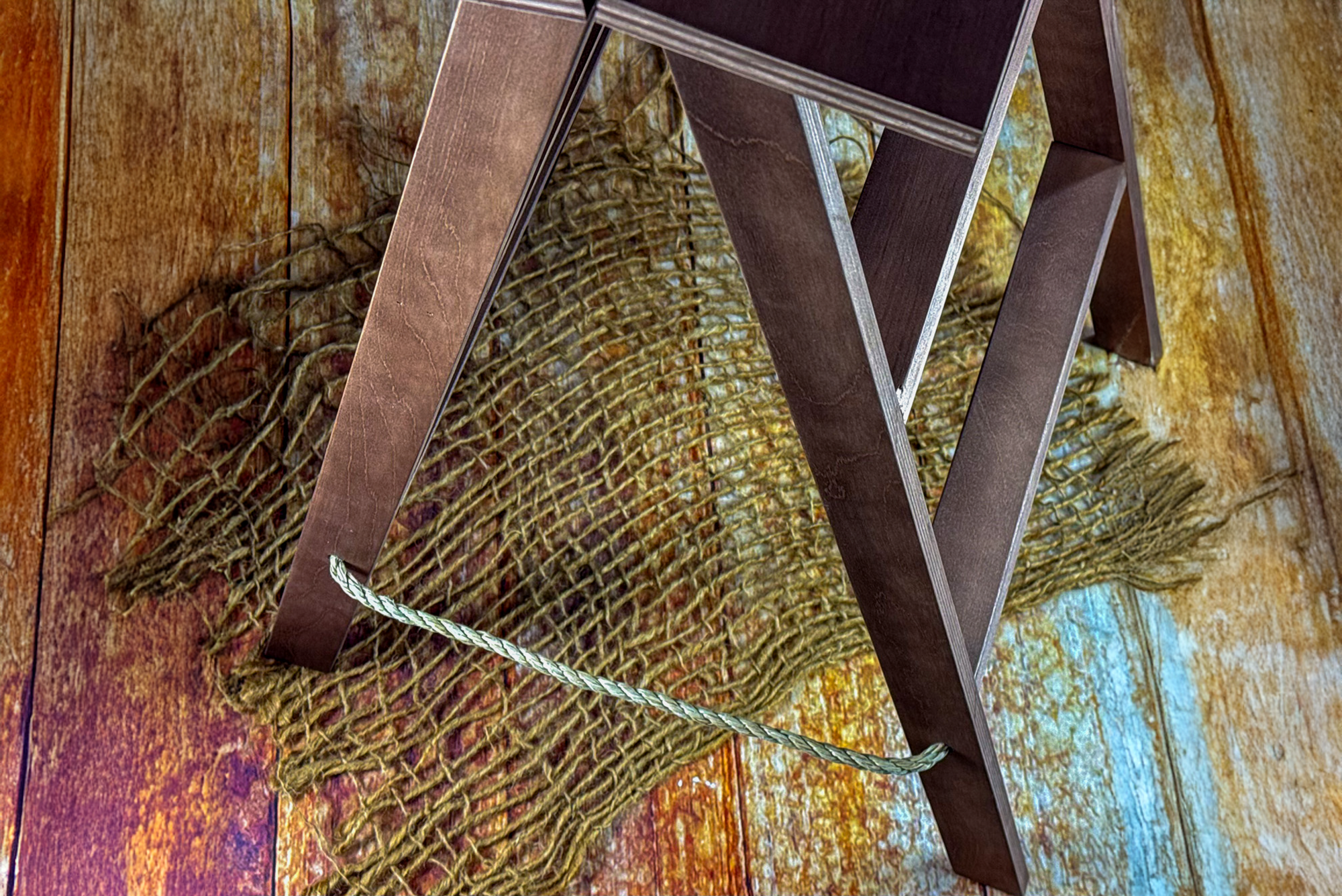 Close-up of dark brown wooden ladder base on rustic jute mat, a warm-toned newborn photography prop.