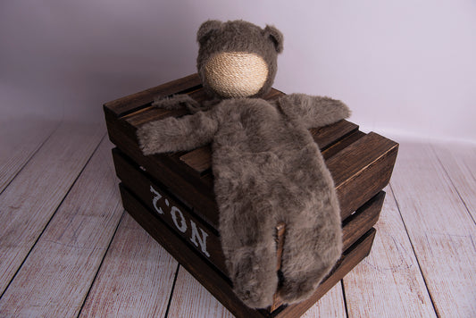 Newborn photography clothing of a bear bonnet and suit in nut brown on a wooden crate.
