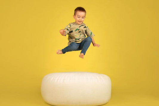 toddler jumping during photo shoot on beanbag for newborn photography