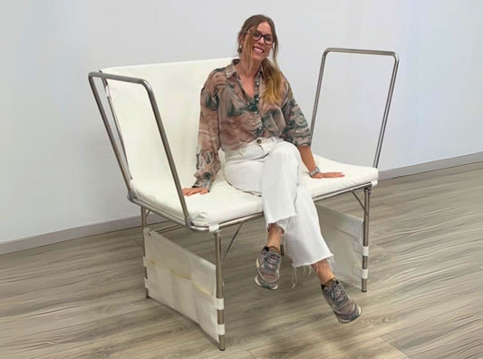 Adult woman sitting on a newborn photography posing table to demonstrate it's sturdy