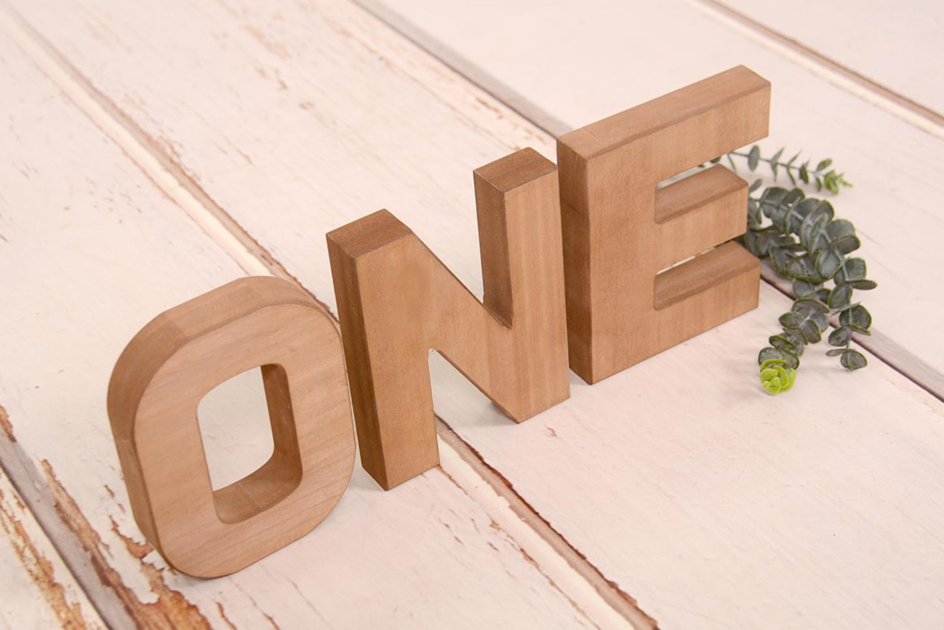 Brown wooden letters spelling out 'ONE' on a rustic wooden background, ideal for cake smashes or milestone photography.