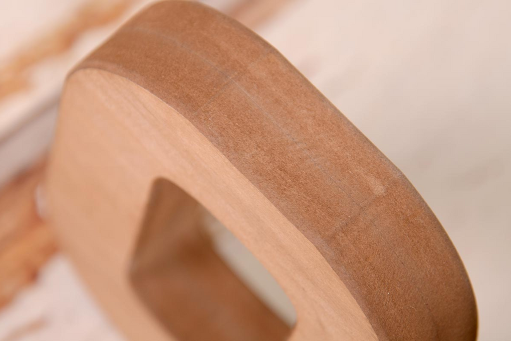 Brown wooden letters spelling out 'ONE' on a rustic wooden background, ideal for cake smashes or milestone photography.