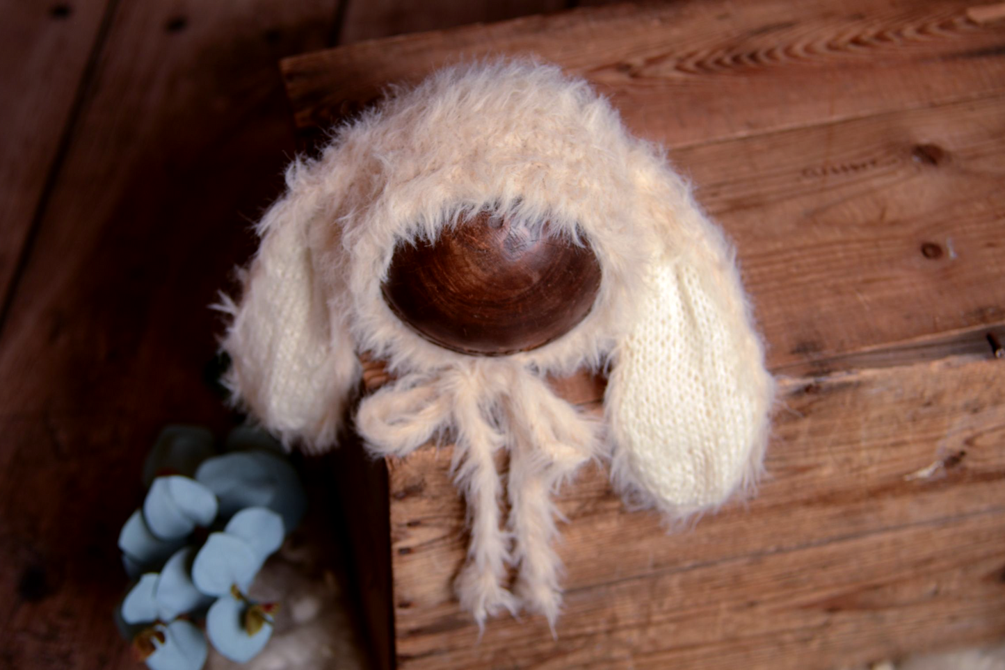 Beige fluffy newborn bunny hat prop on wooden backdrop, ideal for professional baby photographers.