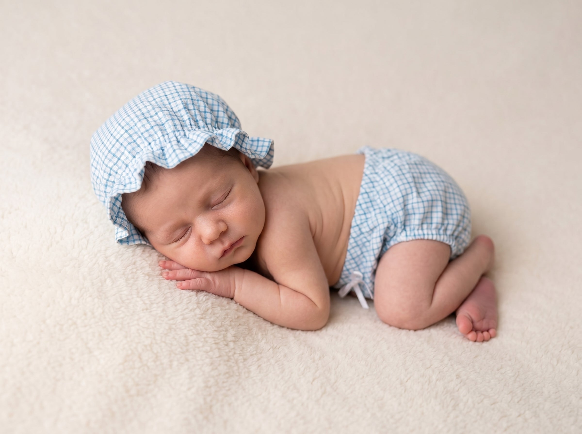 Newborn baby wearing a blue checkered bonnet and diaper newborn photography