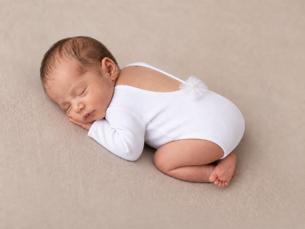Newborn baby in a white bodysuit for baby photography