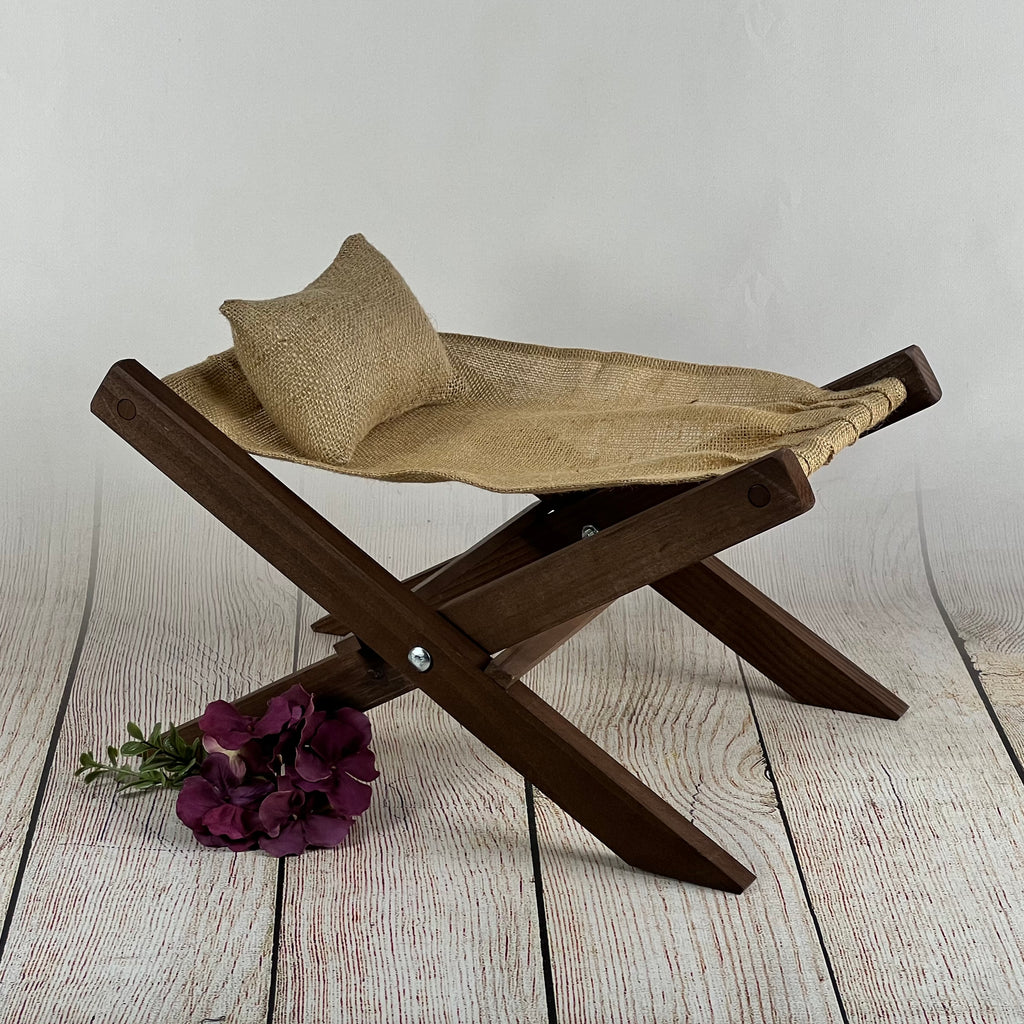 Rustic wooden deck chair with natural burlap seat and pillow, accented by a purple flower. Perfect newborn photography prop.