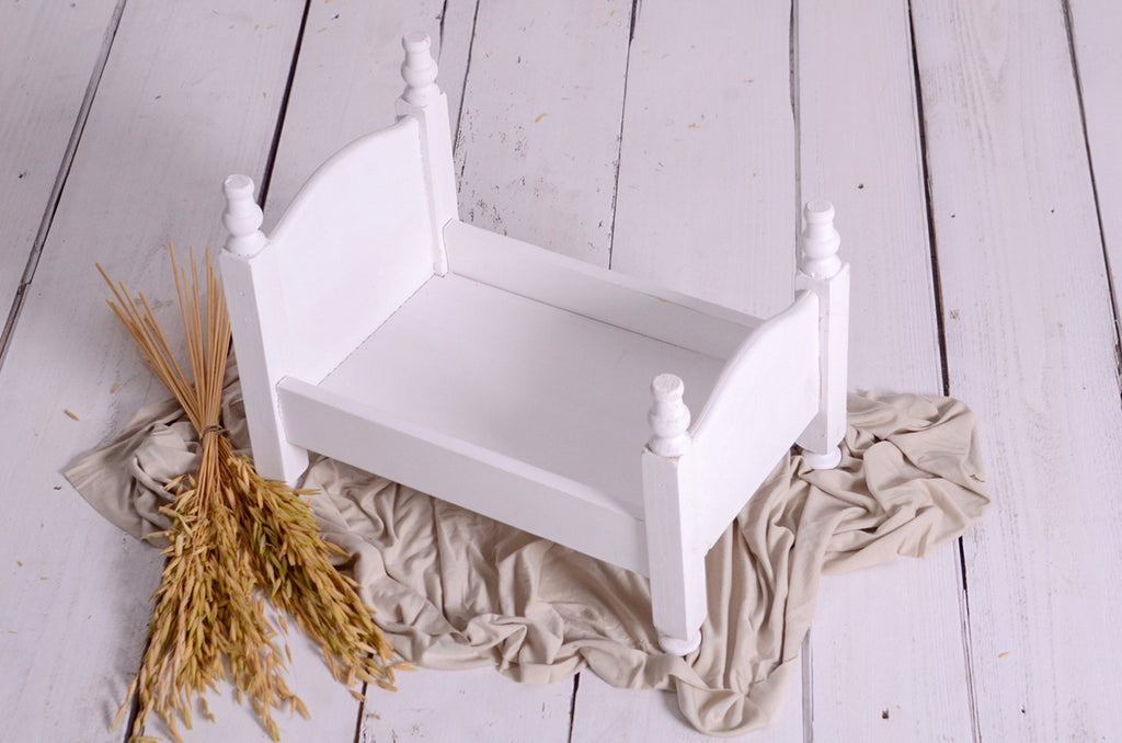 Overhead view of white wooden bed staged with rustic cloth and wheat, newborn photography prop.