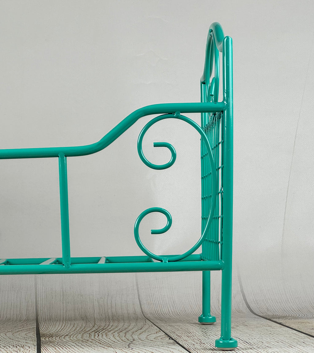 Stylish green metal prop bed with artistic wirework, perfect for newborn photography setups on a wooden floor.