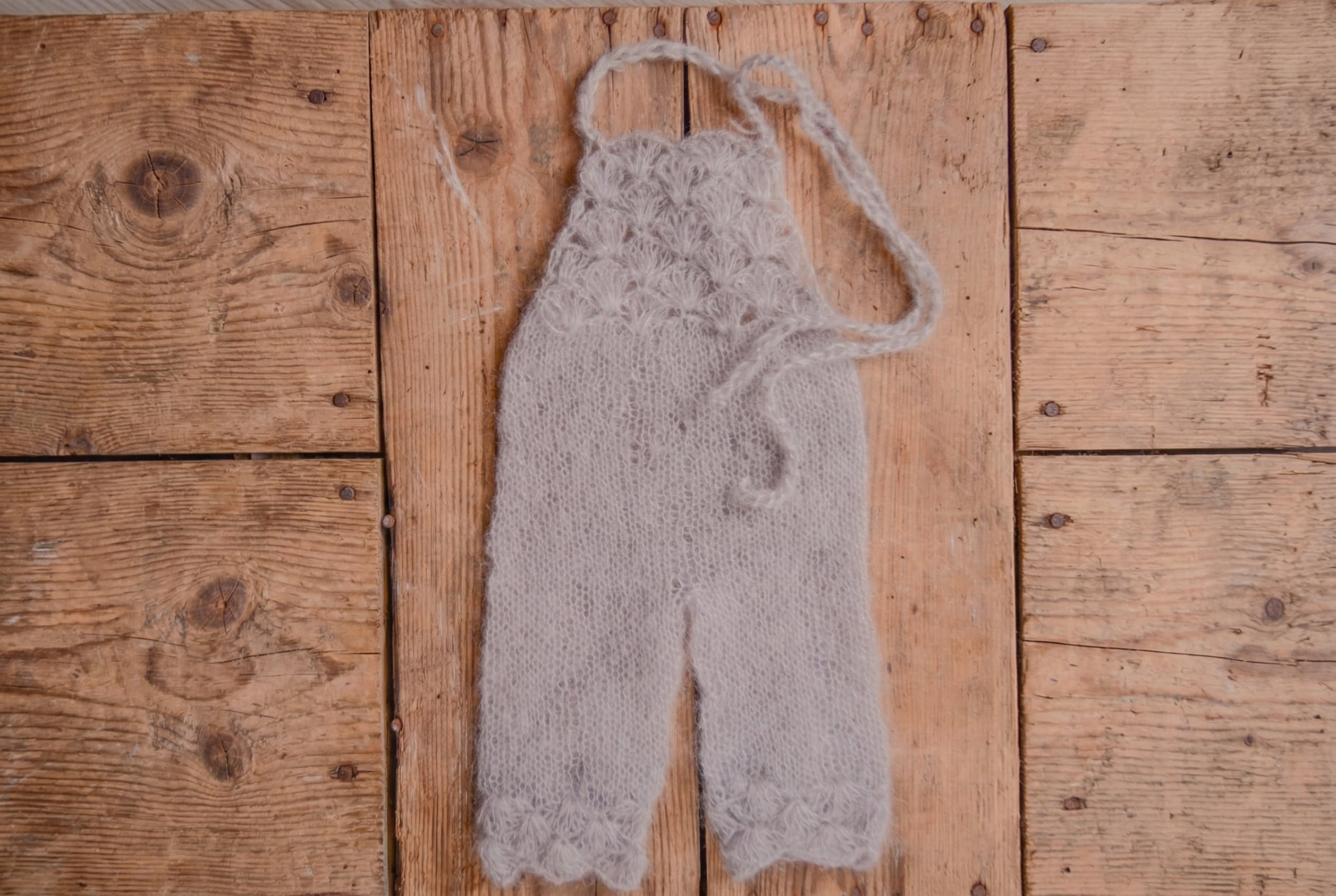 Knitted baby romper on a wooden surface