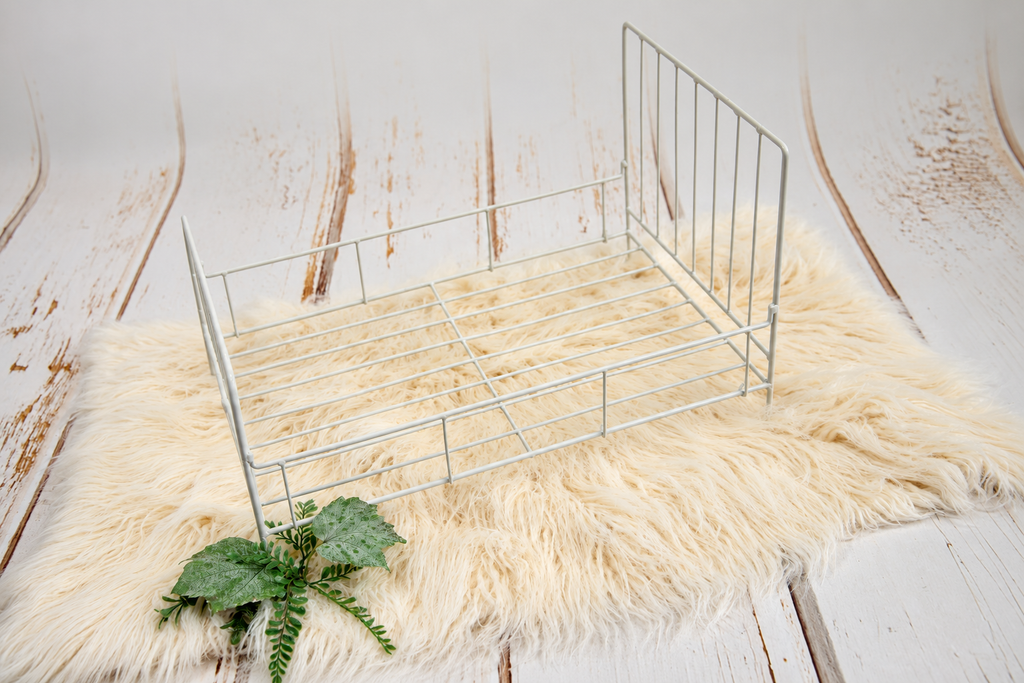 White vintage wire metal bed prop for newborn photography, featuring an open slatted base and delicate metal rails in a professional studio setting.