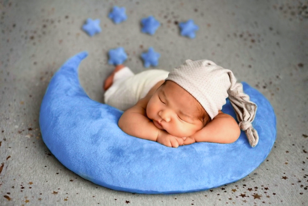 Sleeping baby posed on blue moon pillow set, dreamy newborn photography prop with star accents.