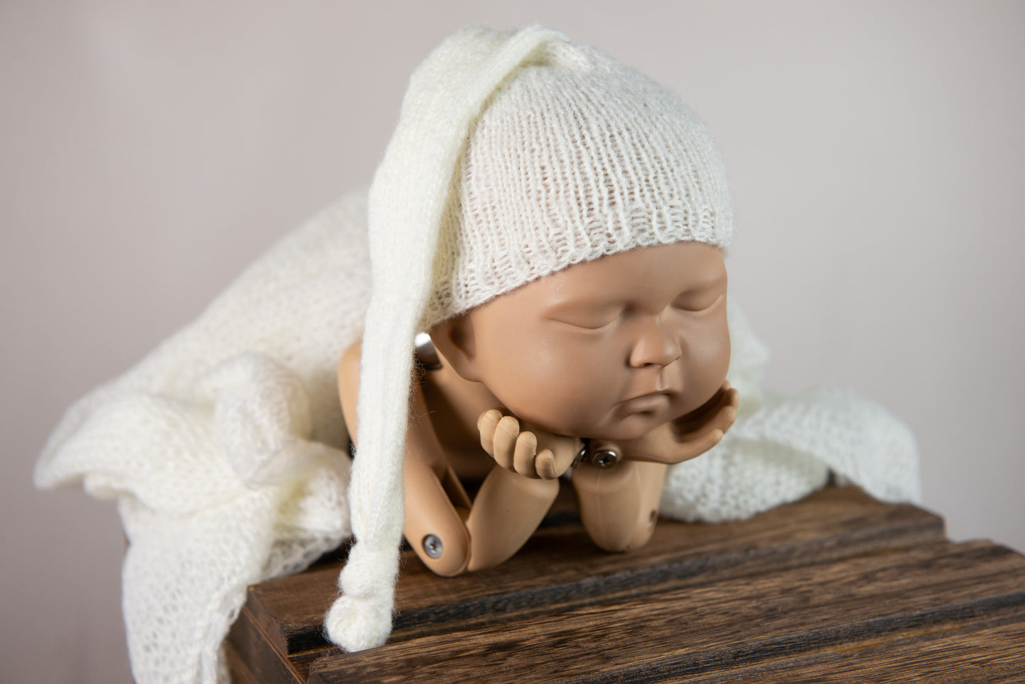 Gray knit hat on sleeping doll showcases newborn photography prop versatility.