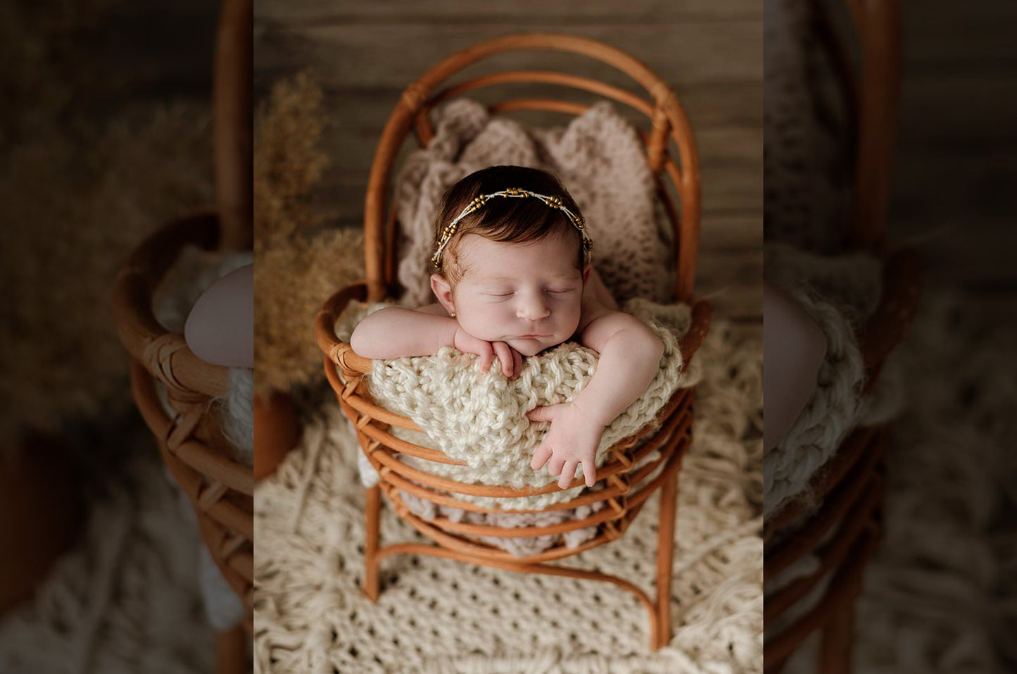 Newborn peacefully posed in a rattan cradle, wrapped in cream knit layers, wearing a delicate gold headband. Newborn photography prop bed.