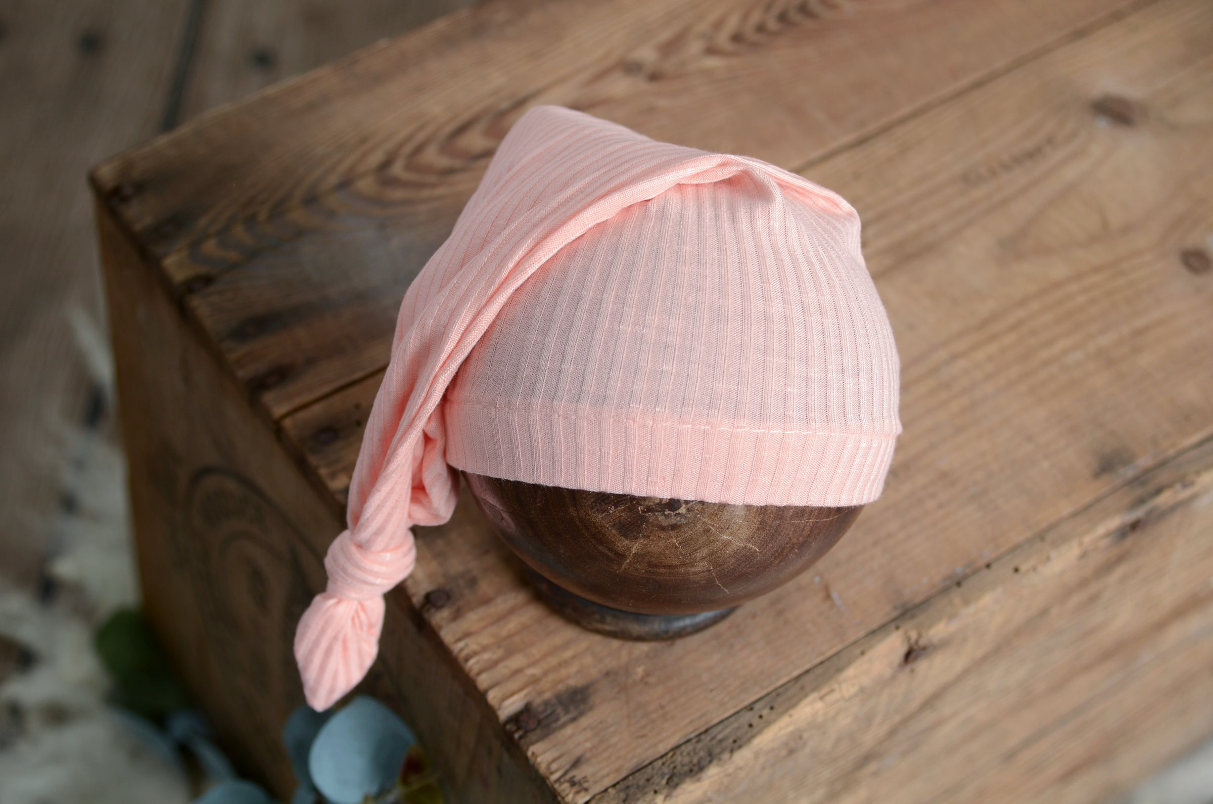 Pink baby hat on a wooden block with a blurred background