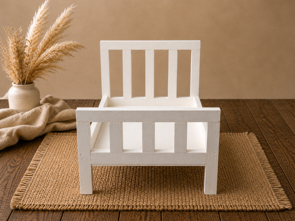 White wooden bed with straight headboard on a wooden floor setup for baby photography