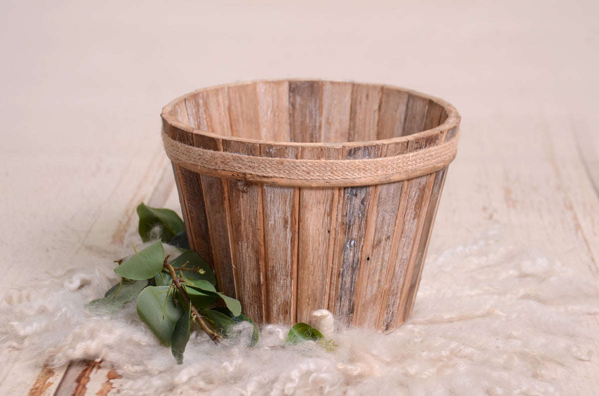 Rustic wooden bucket with a rope-rim detail and driftwood texture, perfect as a newborn photography prop.