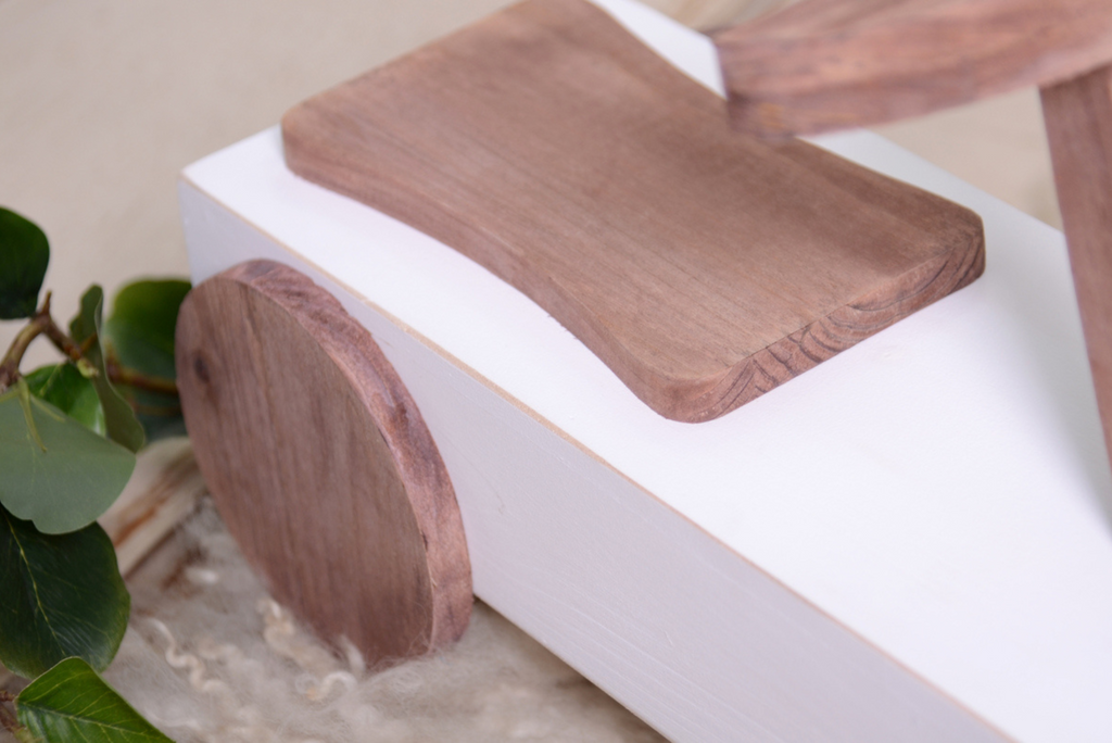 Close-up of the wooden seat and wheel of the Rustic Ride-On - White, highlighting its handcrafted details, perfect for vintage newborn photography themes.