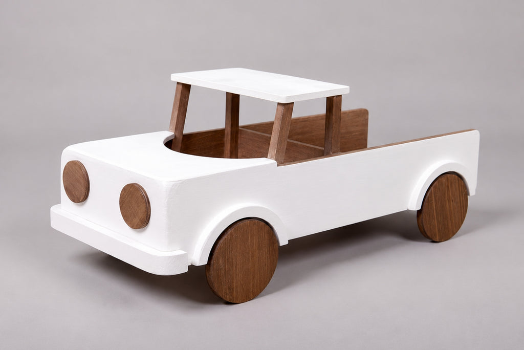 A minimalist wooden toy pickup truck for cake smash photography with a white-painted body and natural brown wood accents for the wheels, bed interior, and canopy,
