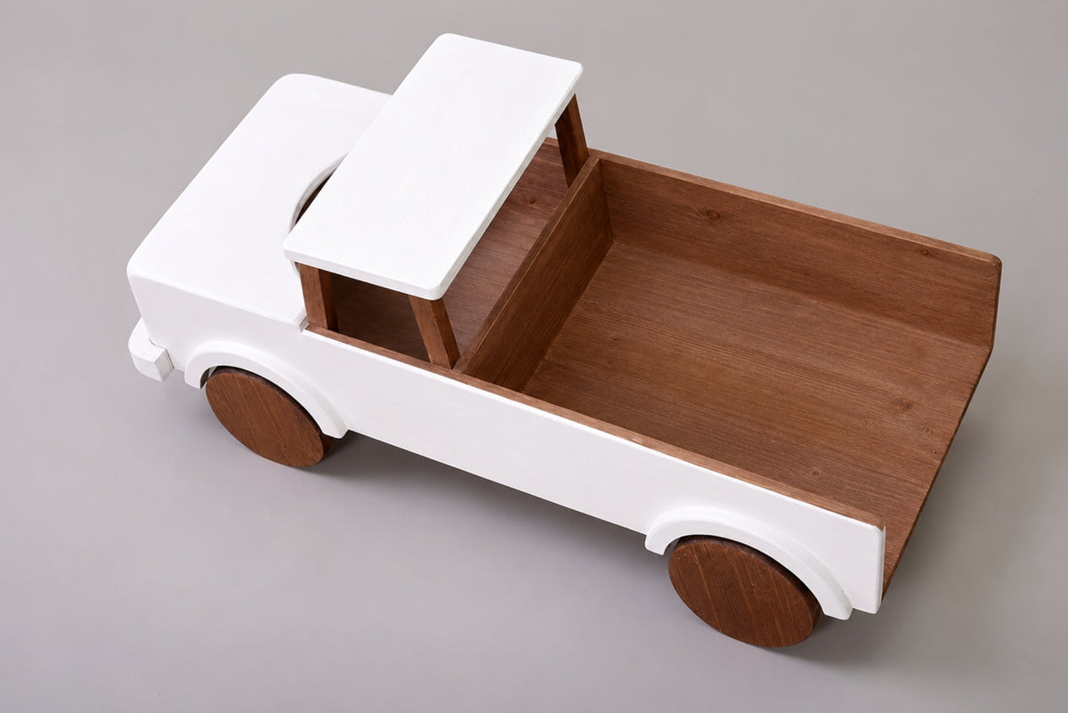A wooden pickup truck with a white-painted body and cab, and a natural brown wood bed and wheels, idal for cake smash photography