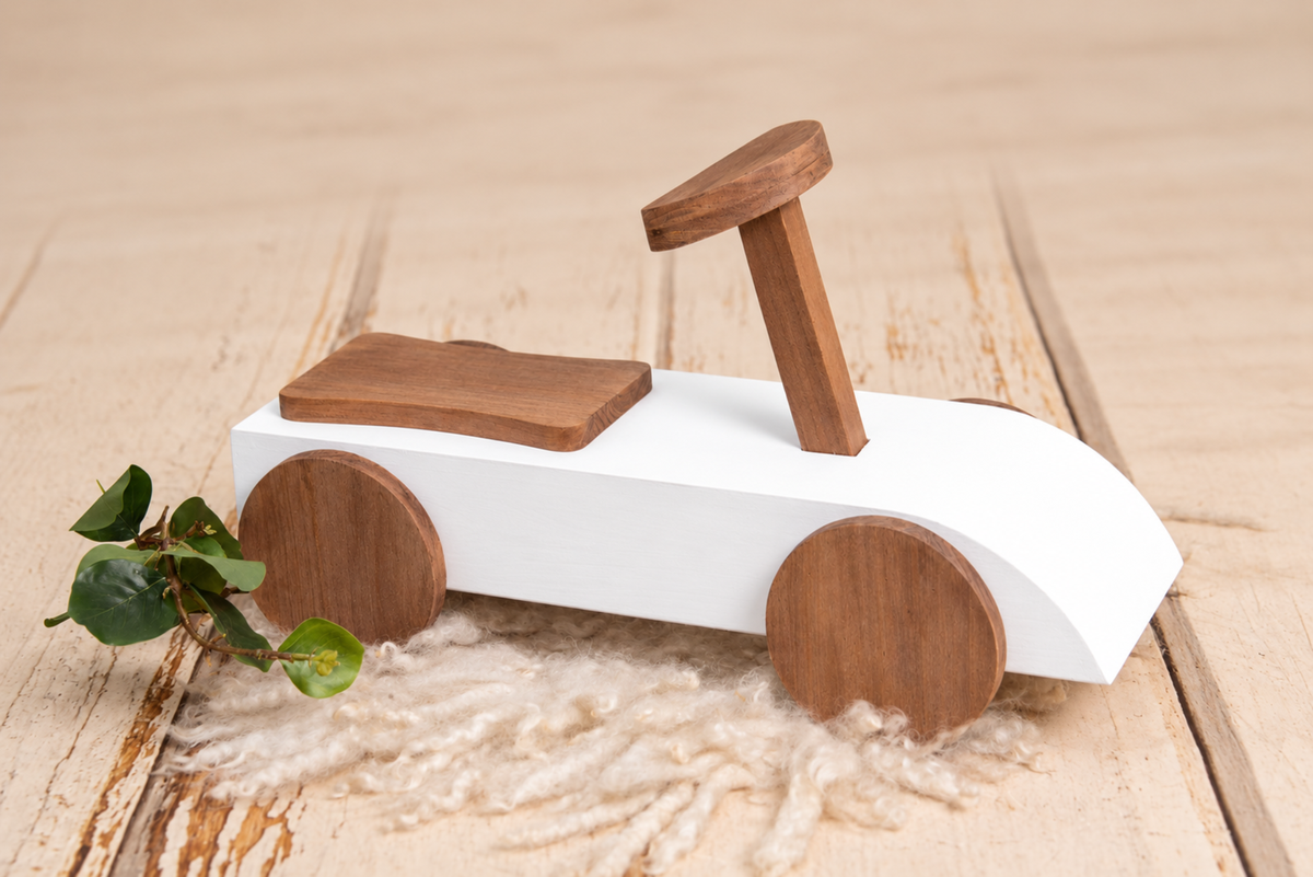 Close-up of the Rustic Ride-On - White, styled with a small wooden "1" and greenery, set on a neutral backdrop for a timeless newborn photography prop setup.