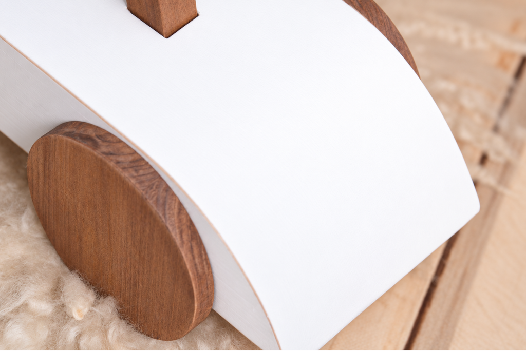 Close-up of the Rustic Ride-On - White's wooden wheel and curved frame, emphasizing its rustic charm as a newborn photography prop.