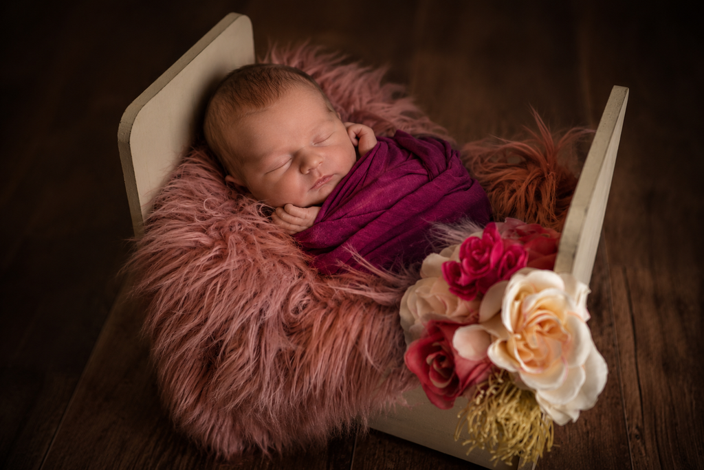 Newborn baby wrapped and sleeping in vintage crib for newborn photography