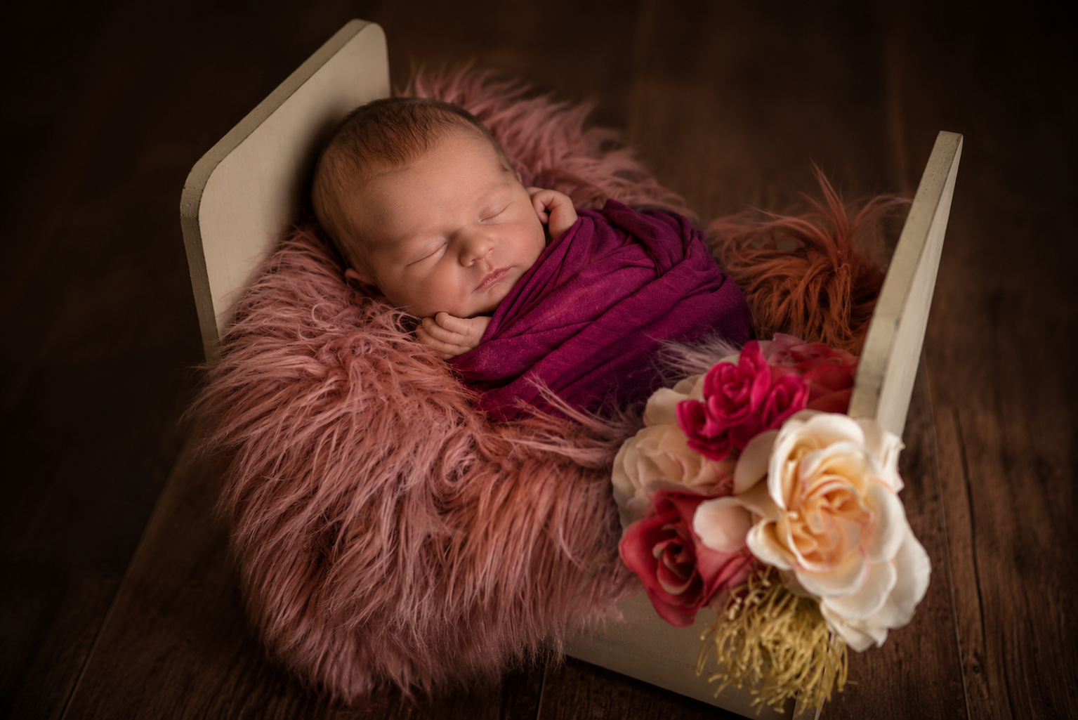 Newborn baby wrapped and sleeping in vintage crib for newborn photography