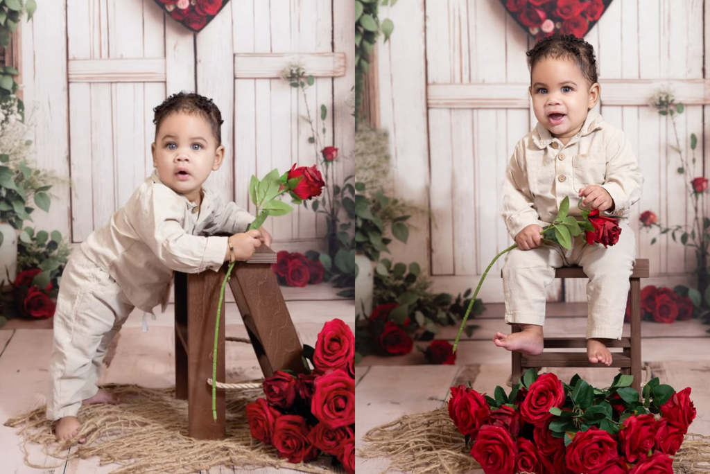 Rustic wooden step ladder mini used as a newborn photography prop in a charming Valentine’s-themed setup. A baby in a neutral beige outfit holds a red rose, posing with the wooden prop against a white barn door backdrop adorned with heart-shaped floral decor. The scene is completed with red roses and woven textures, creating a warm, romantic feel.