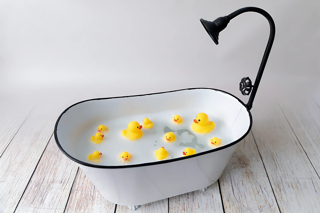 Newborn photography prop white vintage tub filled with bubbles and floating yellow rubber ducks.