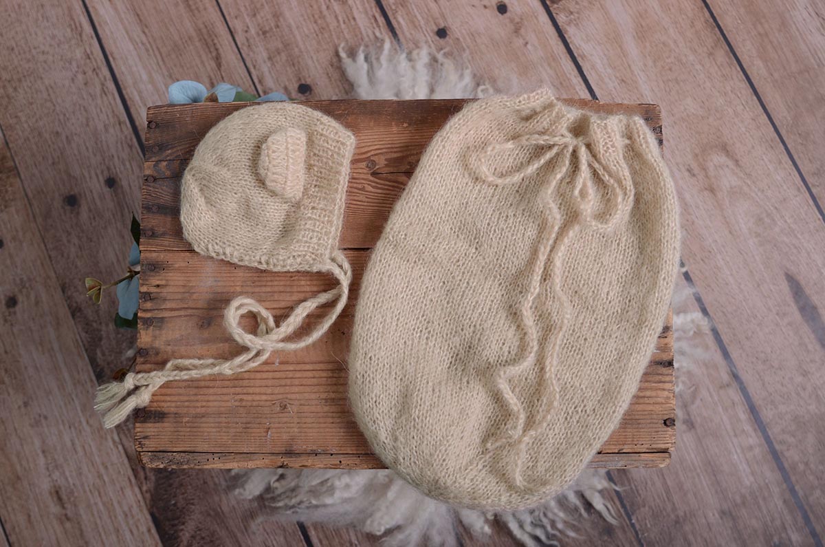 Display of beige mohair bear bonnet and matching sack on a rustic wooden crate, showcasing the newborn photography prop's texture and handmade quality.