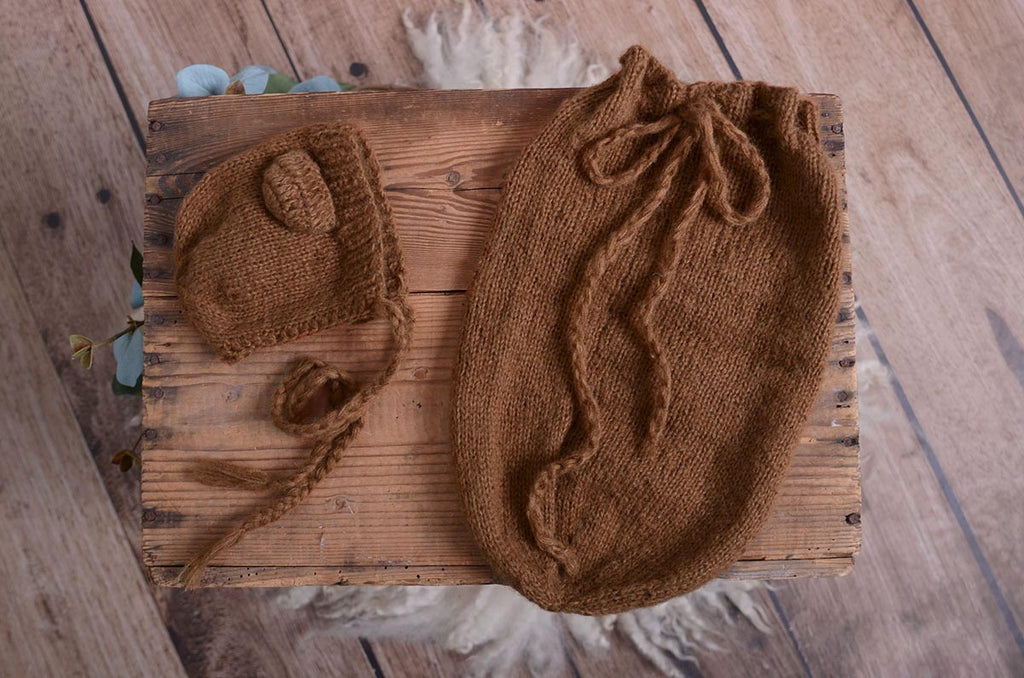 Display of beige mohair bear bonnet and matching sack on a rustic wooden crate, showcasing the newborn photography prop's texture and handmade quality.