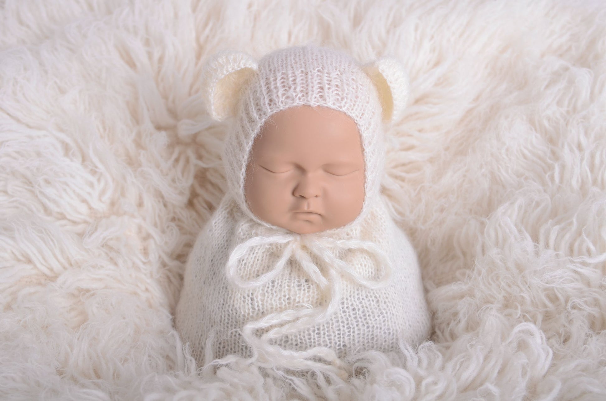 Newborn photography prop featuring a beige mohair bear bonnet and sack on a plush white background, designed for a serene and soft aesthetic.