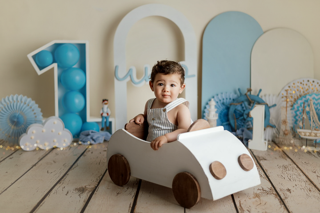 Baby boy sits in white Beetle Cabrio baby photography prop with nautical and first birthday decor. Great for milestones sessions.