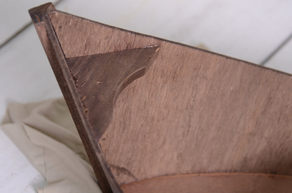 Close-up of pointed end of wooden rowboat, highlighting craftsmanship of this newborn photography prop.