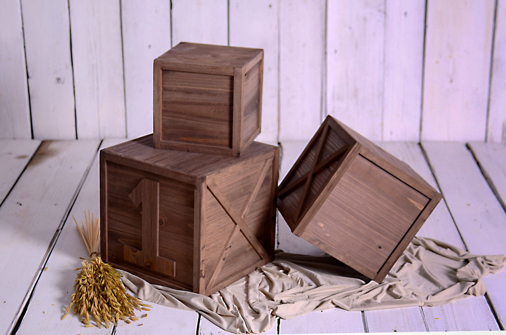 Wooden crates styled for milestone sessions, one tipped playfully, newborn photography prop for cakesmash.