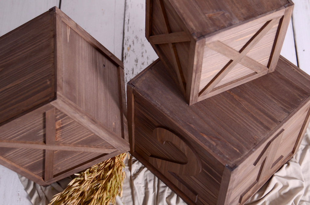 Top-down view of three brown milestone boxes with engraved numbers, perfect newborn photography prop.