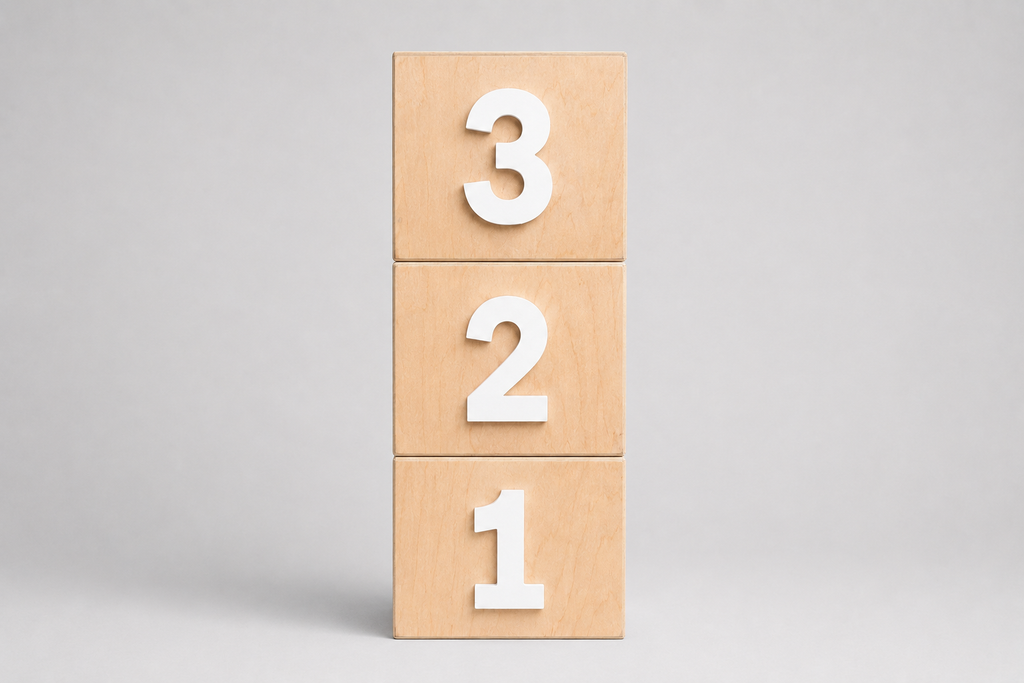 Three stacked light wood smash cake blocks displaying the numbers 3, 2, and 1 in white