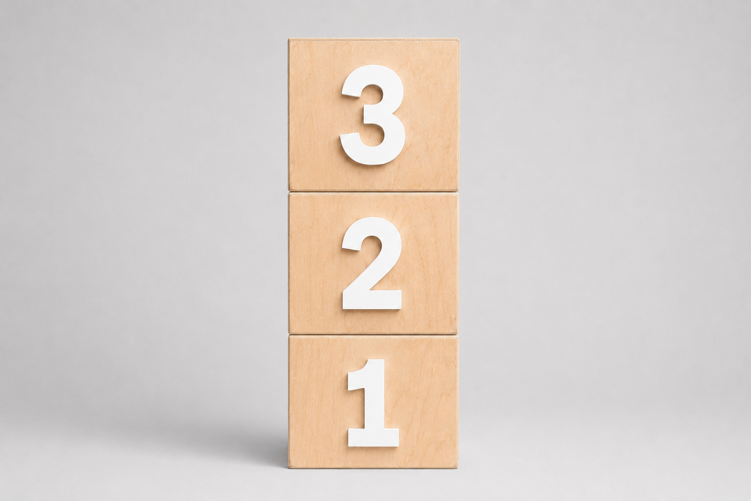 Three stacked light wood smash cake blocks displaying the numbers 3, 2, and 1 in white