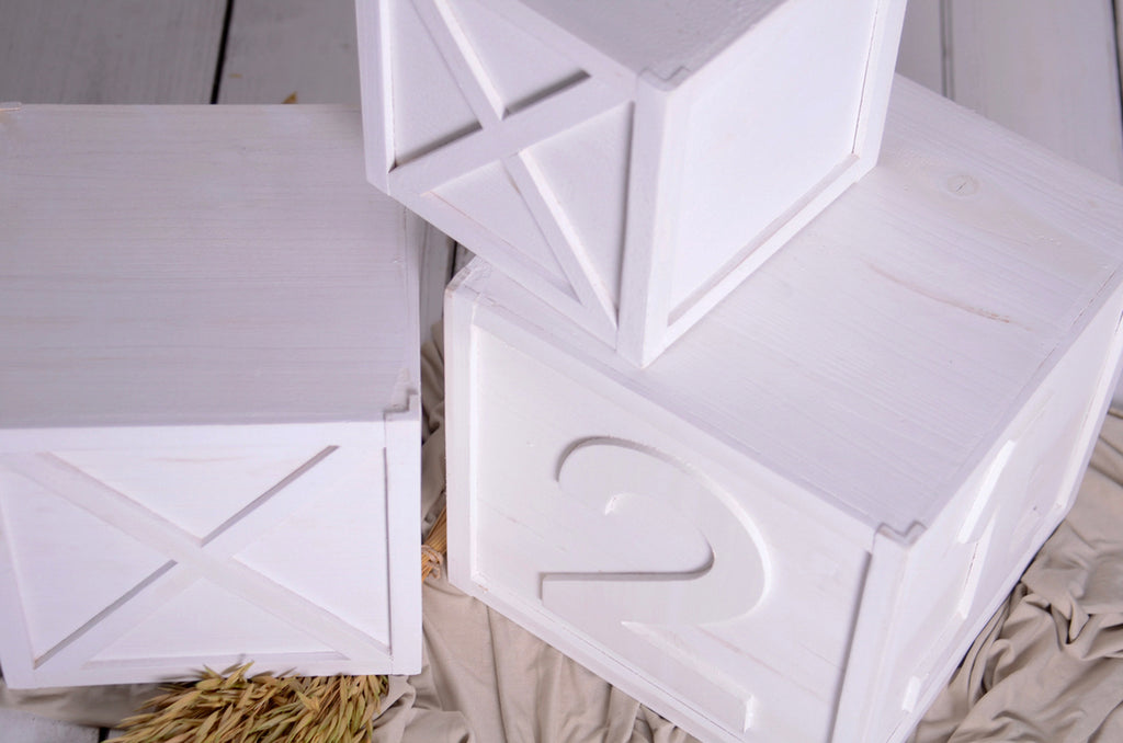 Close-up top view of white milestone boxes with numbers, newborn photography prop for cakesmash use.