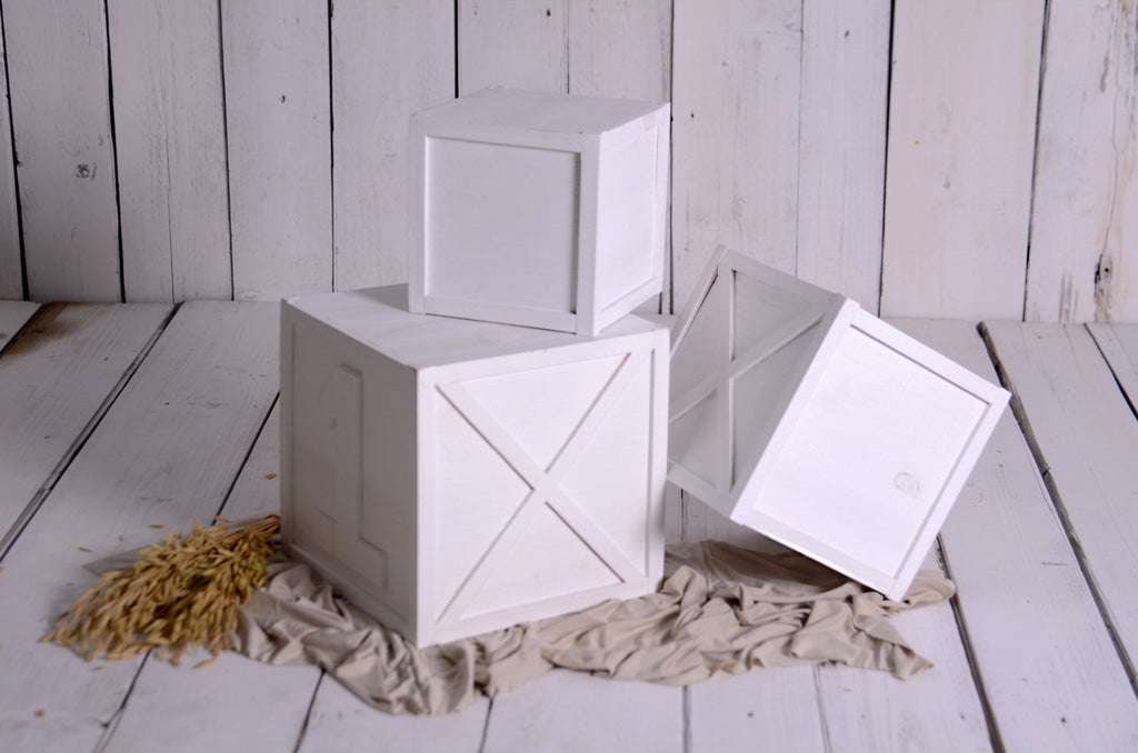 White wood boxes for milestone sessions, one tipped over playfully, newborn photography prop.