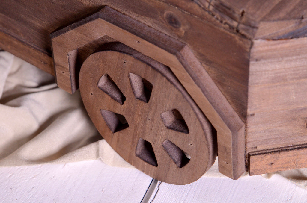 Close-up of carved wooden wheel detail on modern cyber truck-style newborn photography prop.
