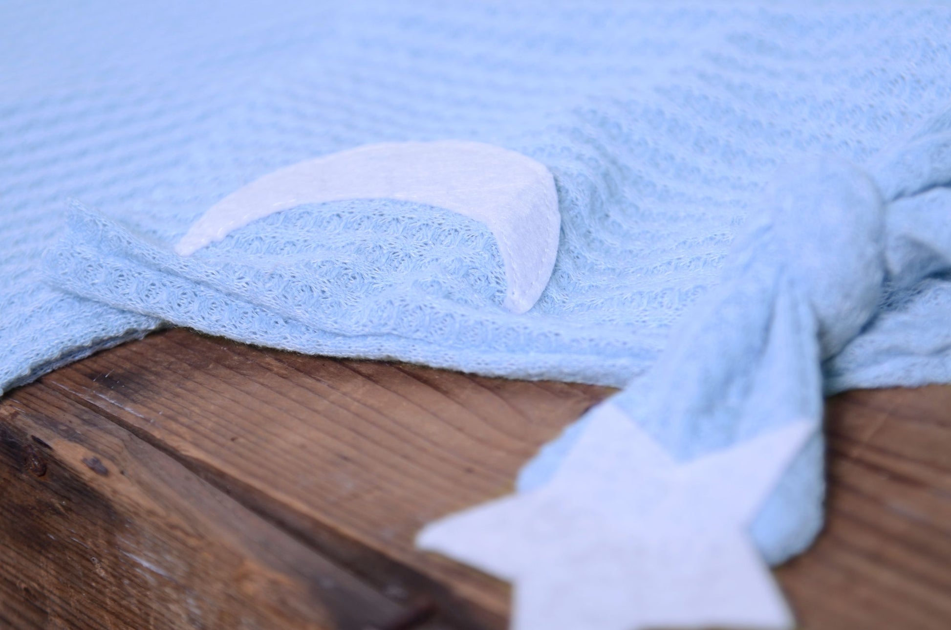 Light Blue waffle fabric footed pajamas and matching hat with moon and stars, displayed as a newborn photography prop on a rustic wooden surface.