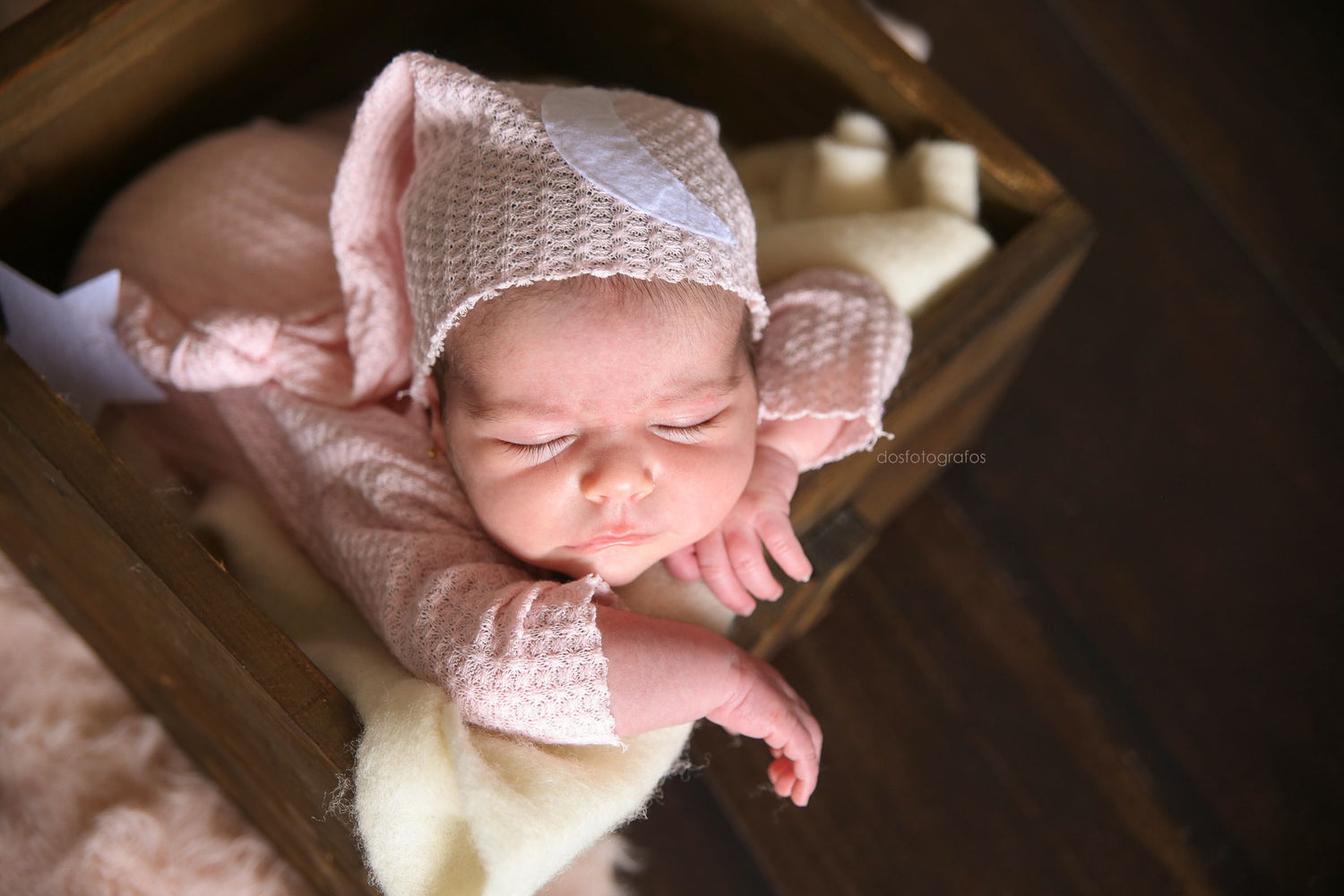 Baby wearing Pink waffle fabric footed pajamas and matching hat with moon and stars, displayed as a newborn photography prop on a rustic wooden surface.