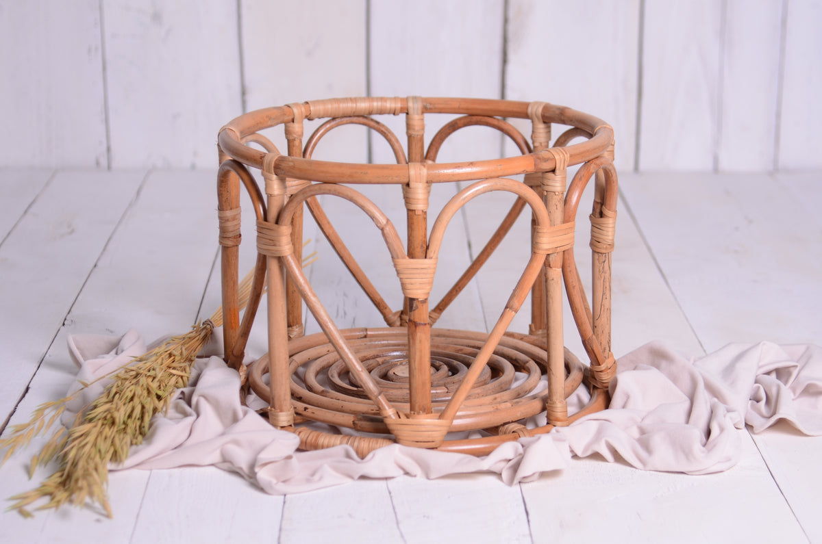 A rustic LovePod rattan basket, ideal for newborn photography props, styled with neutral fabric and dried wheat.