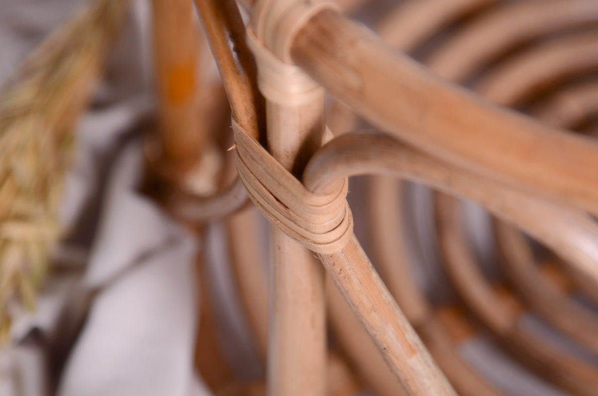 A charming LovePod rattan basket closeup, a versatile newborn photography prop, styled with soft beige fabric on a wooden backdrop.